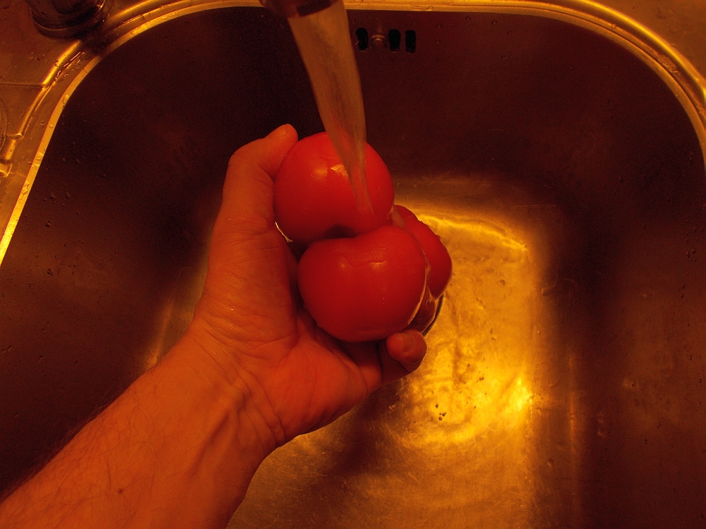 Waschen Sie die Tomaten mit kaltem Wassern und vierteln Sie sie. Geben Sie sie anschließend in die Salatschüssel.